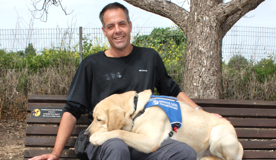 Israel Guide Dog and Veteran sitting on the bench.